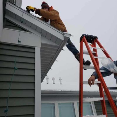 Man putting up holiday lights on home Land Visions Lansing Michigan